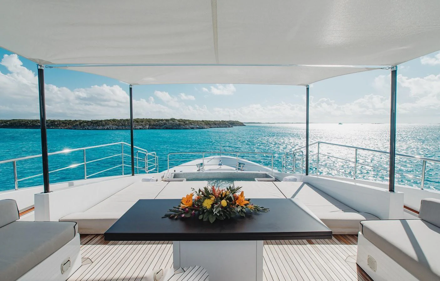 The aft deck offers a serene setting with a central table adorned with flowers, surrounded by comfortable seating and a stunning ocean view. aboard EMINA Yacht for Sale