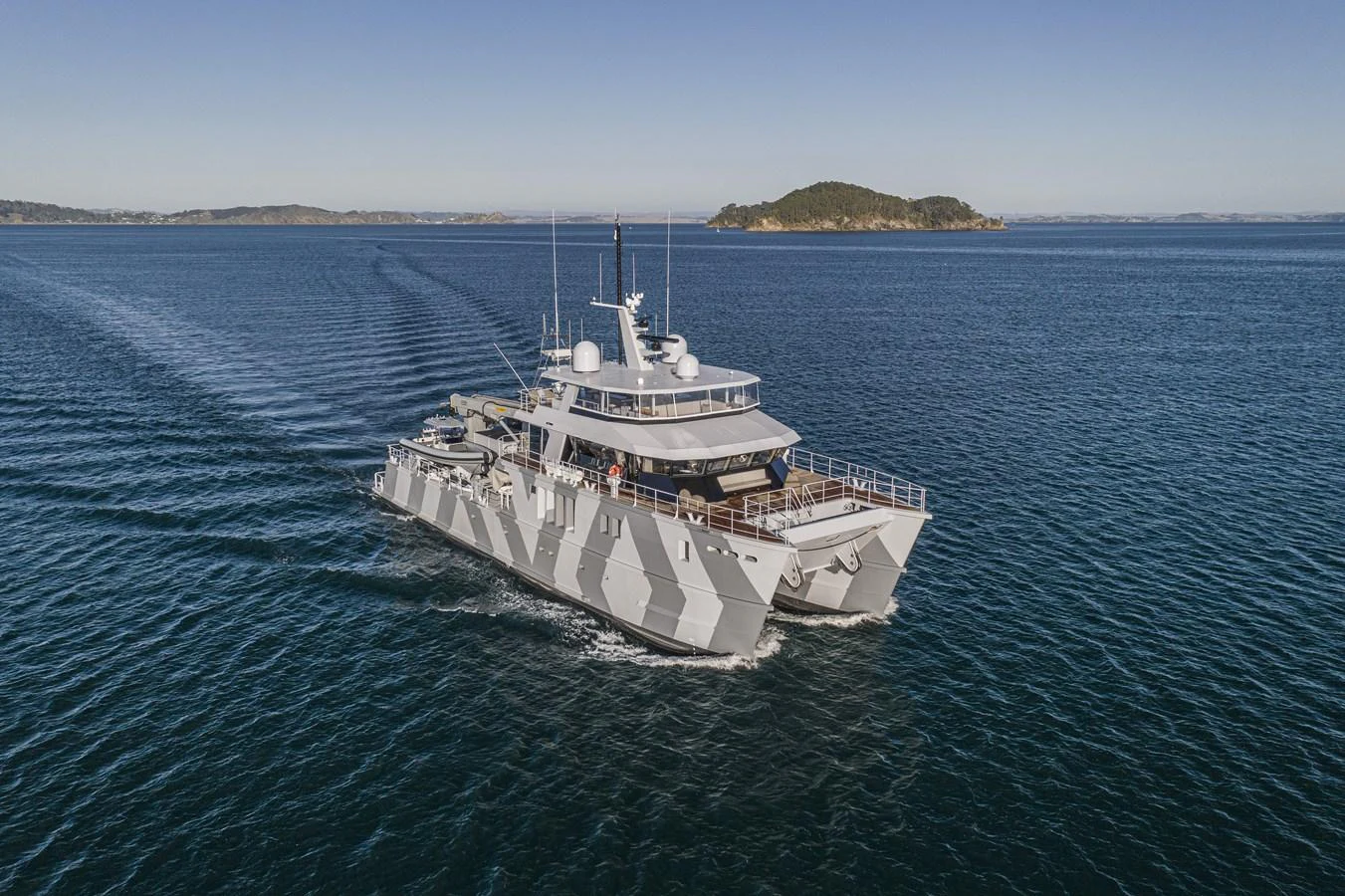 A striking yacht with a unique camouflage pattern cruises through calm waters. aboard THE BEAST Yacht for Sale