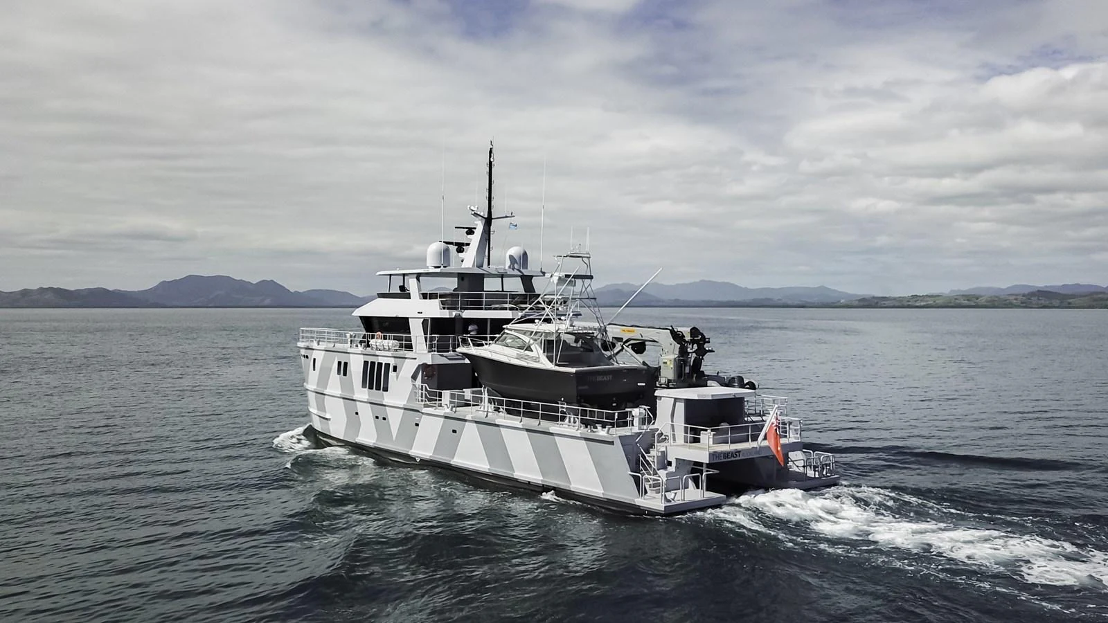 A robust yacht cruises through calm waters under a partly cloudy sky. aboard THE BEAST Yacht for Sale