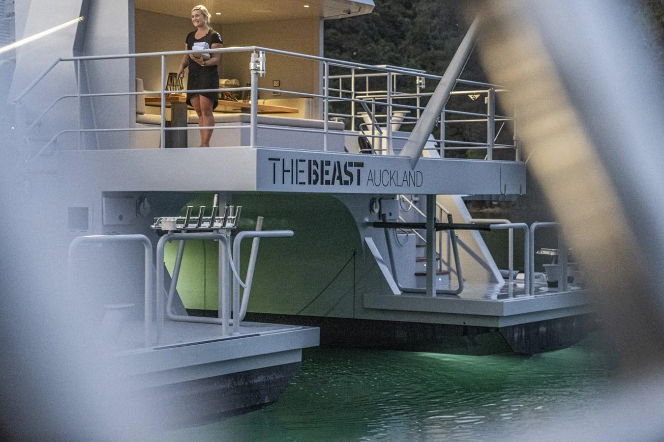 The aft deck of the yacht features a spacious area with a woman standing and enjoying the view. aboard THE BEAST Yacht for Sale
