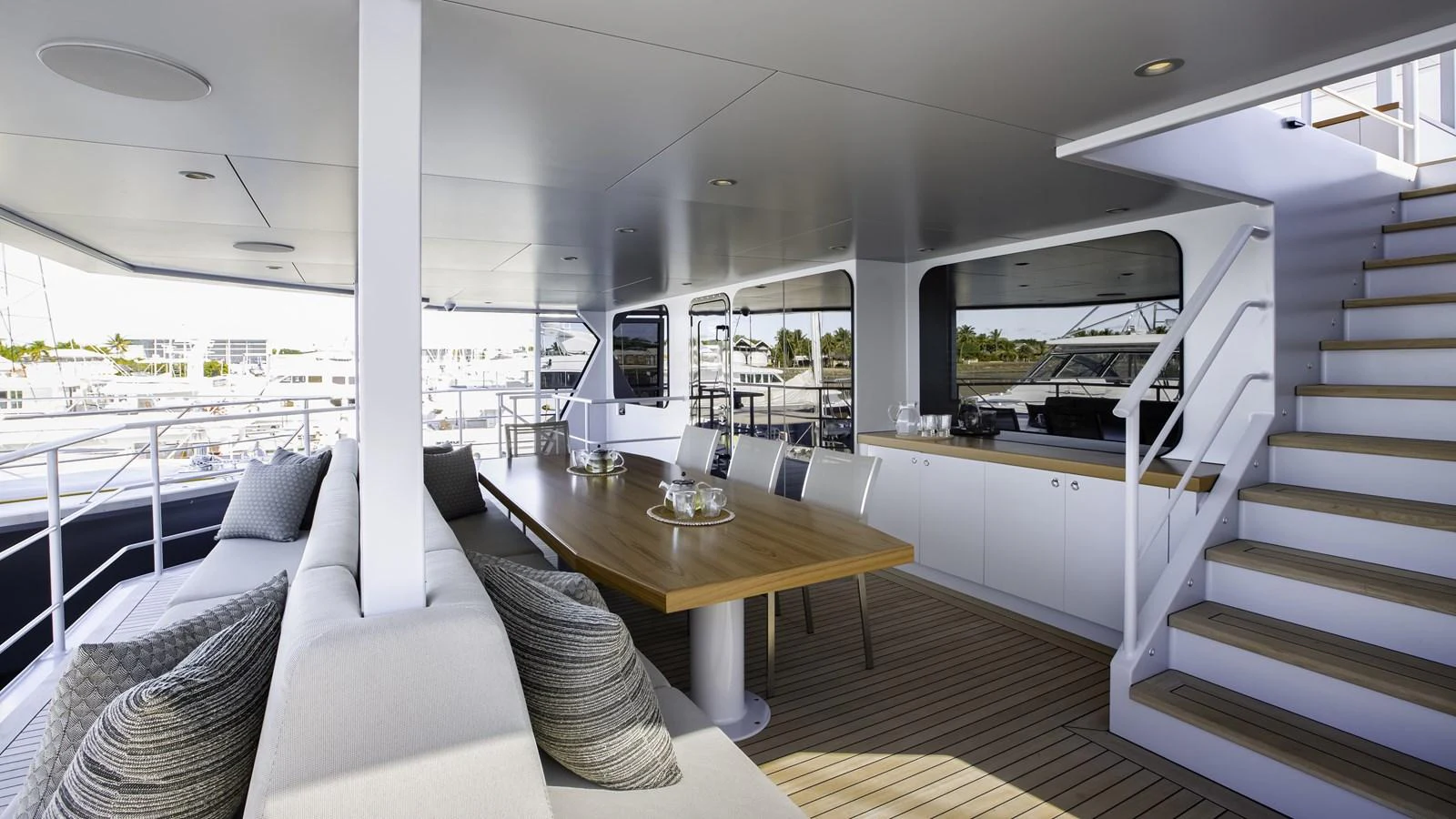 The aft deck features a spacious seating area with a dining table and modern decor. aboard THE BEAST Yacht for Sale