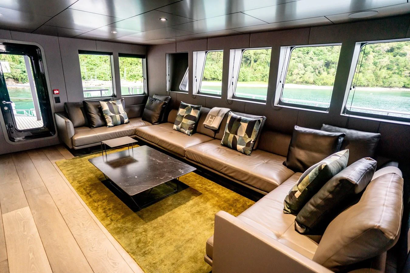 The salon features plush seating with large windows offering scenic views. aboard THE BEAST Yacht for Sale