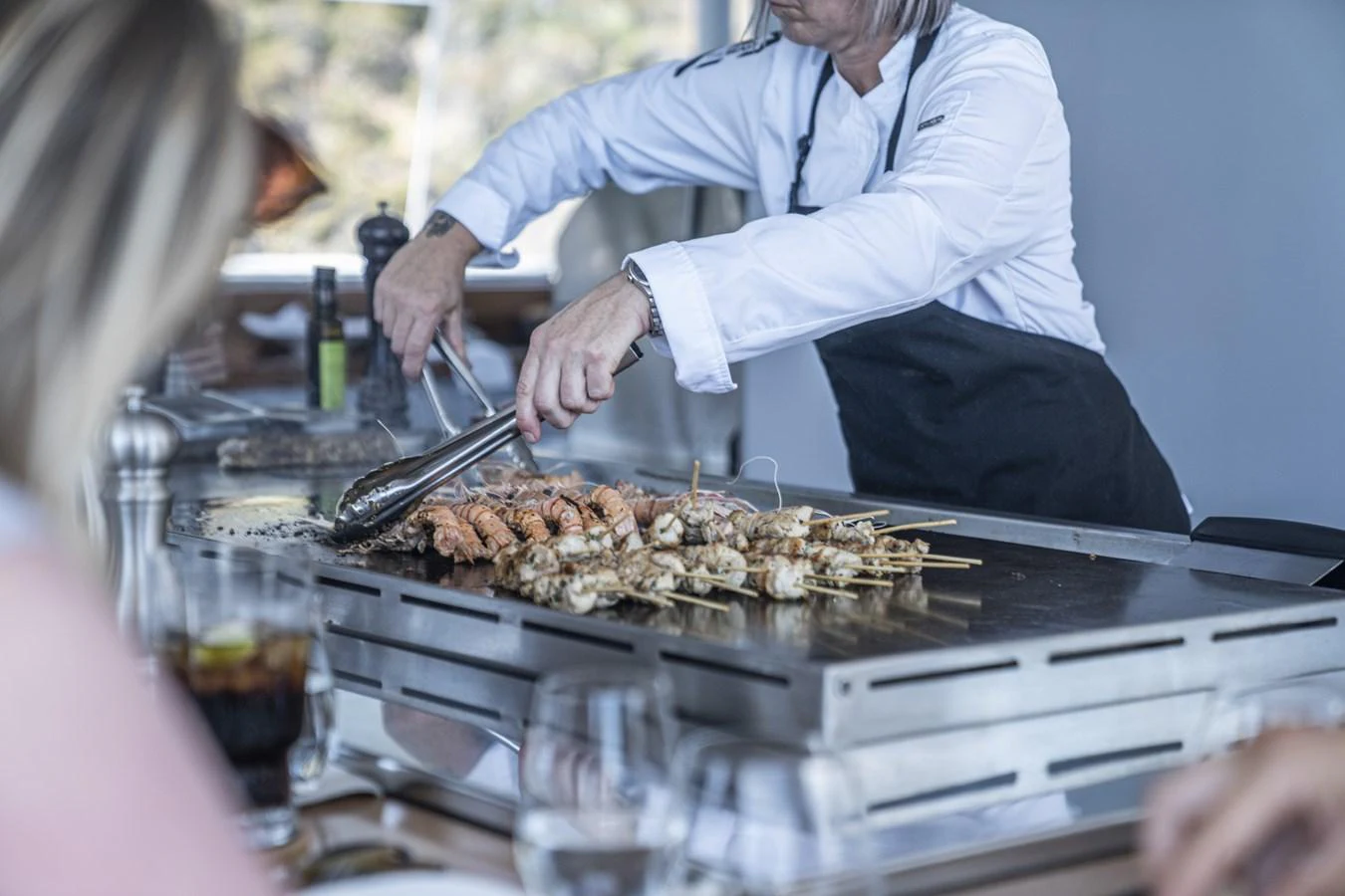 A chef prepares skewers on a grill in the yacht's galley, showcasing the culinary amenities available onboard. aboard THE BEAST Yacht for Sale