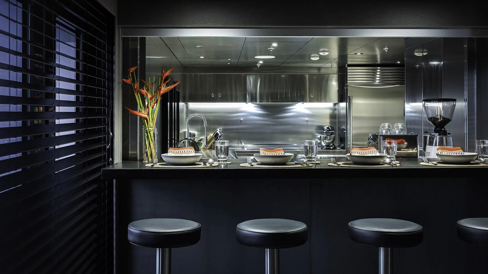 The sleek and modern galley features a stylish bar counter with elegant place settings and contemporary decor. aboard THE BEAST Yacht for Sale
