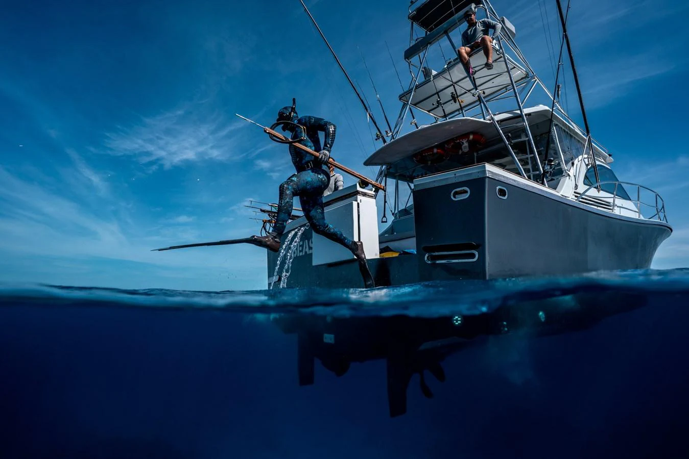 A diver prepares to enter the water from the stern of a yacht, showcasing an adventurous spirit. aboard THE BEAST Yacht for Sale