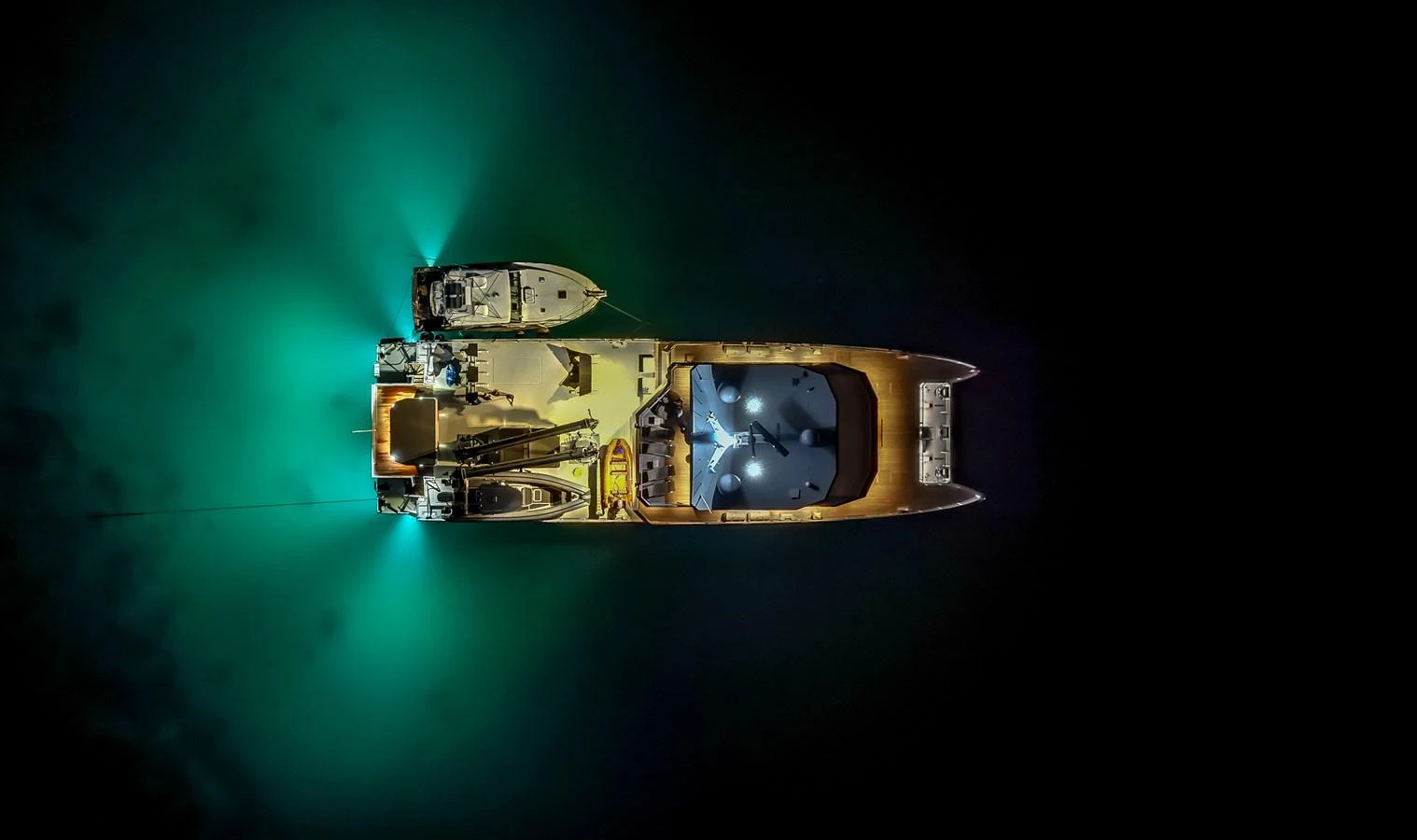A stunning aerial view of a yacht illuminated at night, showcasing its elegant design and underwater lights. aboard THE BEAST Yacht for Sale