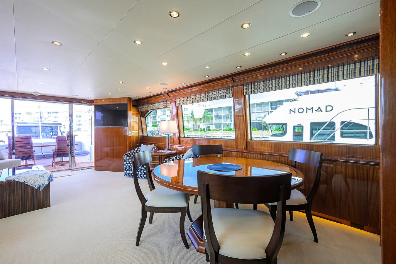 The yacht's dining area features a round table with elegant seating, surrounded by large windows offering a view of the marina. aboard SAPPHIRE Yacht for Sale