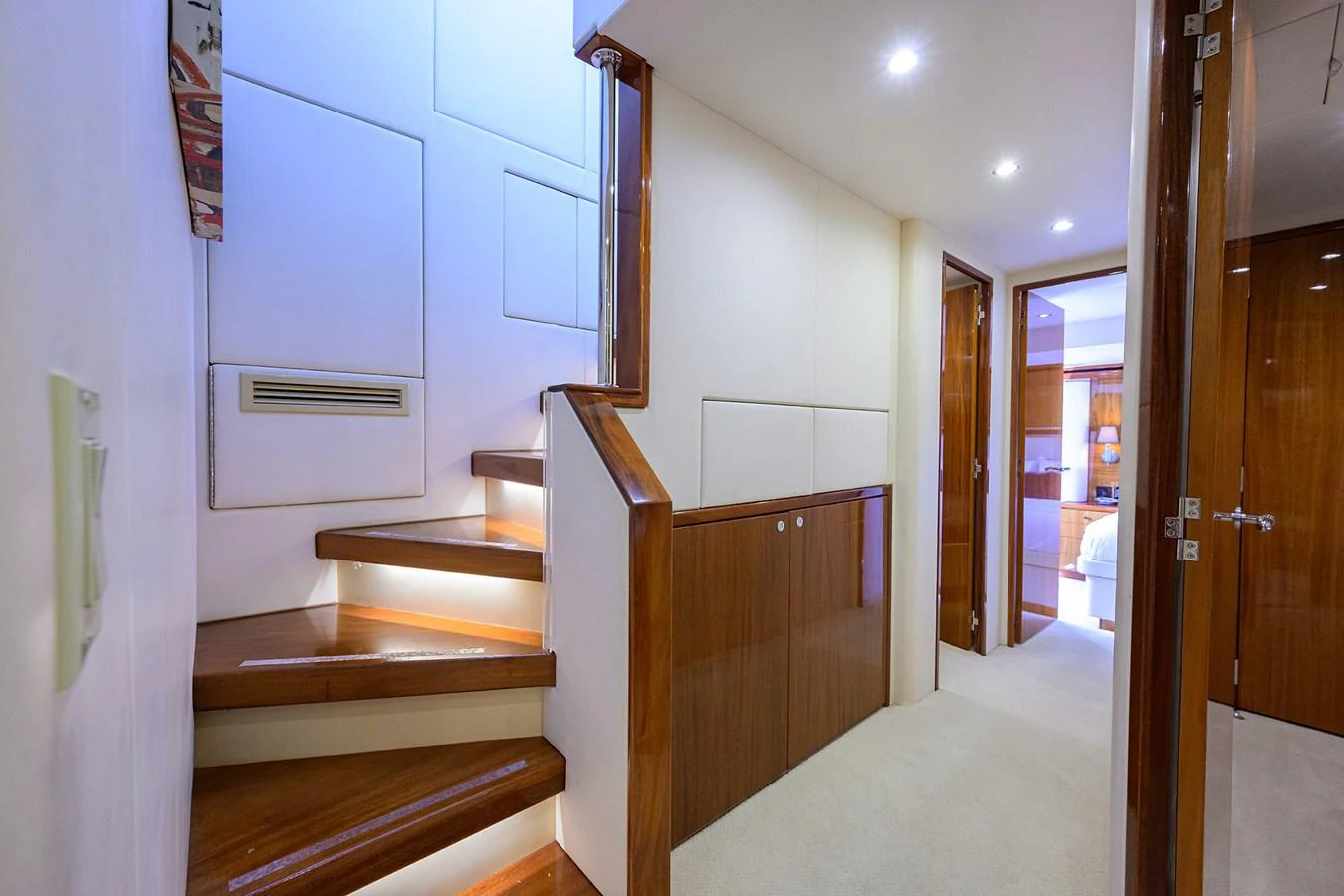 A well-lit interior hallway with wooden stairs leading to another level. aboard SAPPHIRE Yacht for Sale