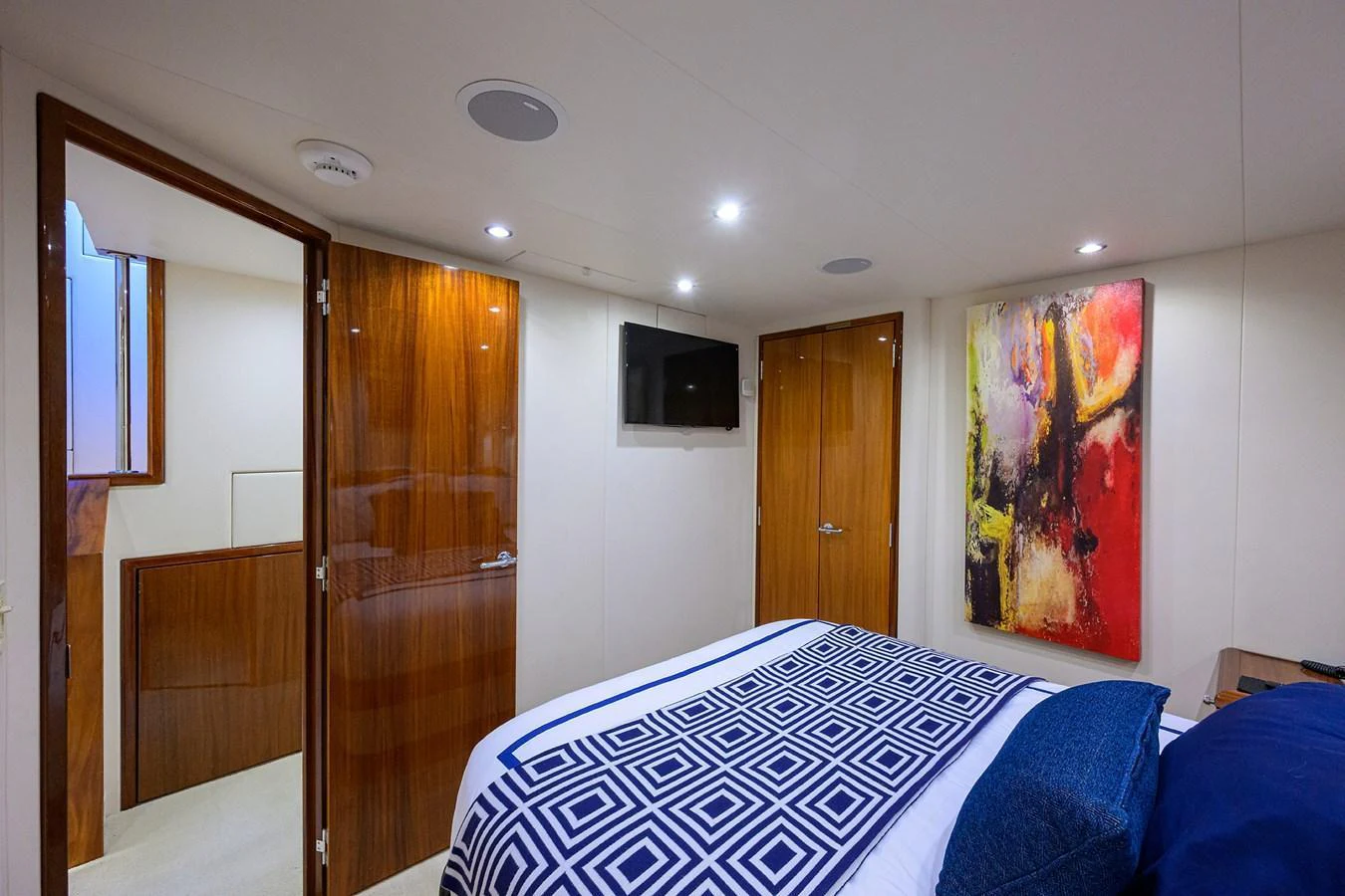The stateroom features a cozy bed with modern decor and vibrant artwork. aboard SAPPHIRE Yacht for Sale
