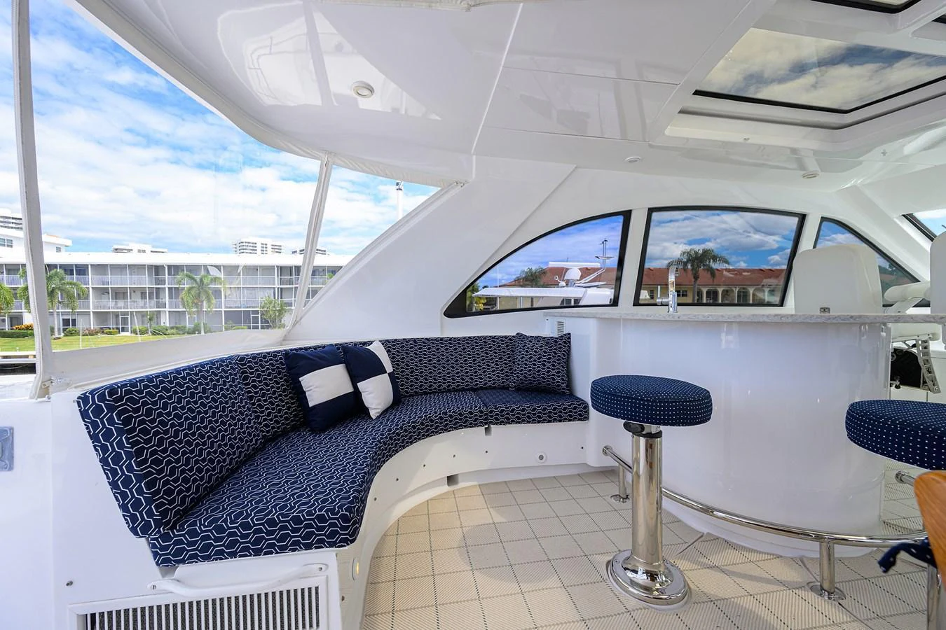 The flybridge features a stylish seating area with a curved sofa and bar stools, perfect for relaxing and entertaining. aboard SAPPHIRE Yacht for Sale