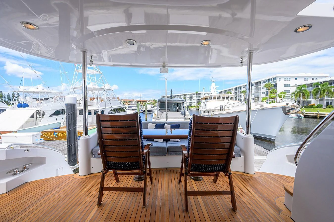 The aft deck offers a serene space with wooden chairs and a table, perfect for enjoying the marina view. aboard SAPPHIRE Yacht for Sale