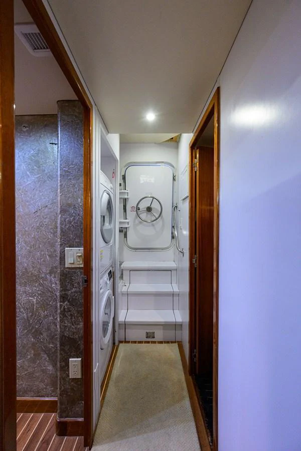 A narrow hallway with a washer and dryer unit leading to a watertight door. aboard SAPPHIRE Yacht for Sale