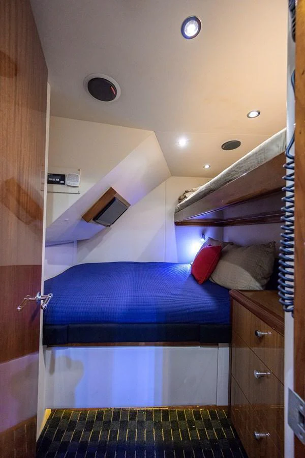 A cozy yacht cabin featuring a double bed with blue bedding and ambient lighting. aboard SAPPHIRE Yacht for Sale