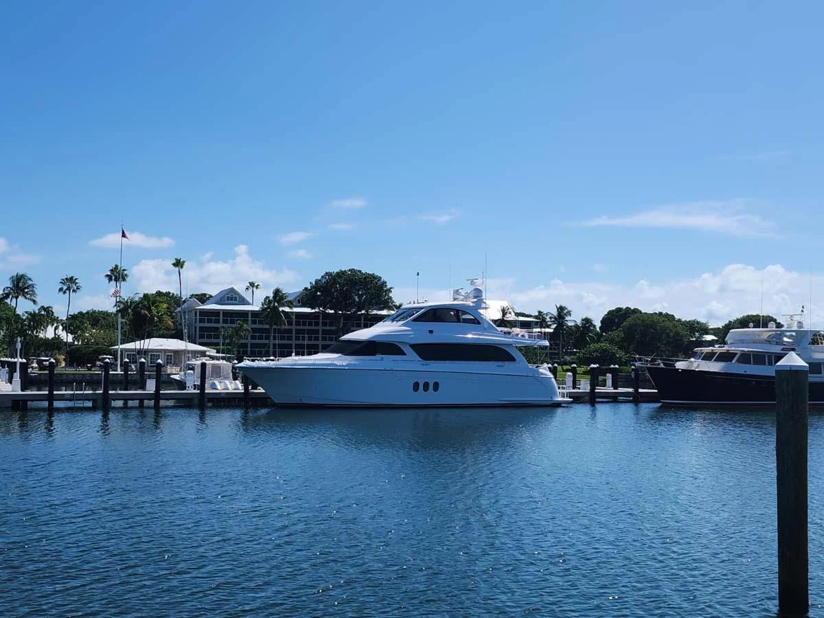 A sleek white yacht is docked in a serene marina under a clear blue sky. aboard SAPPHIRE Yacht for Sale