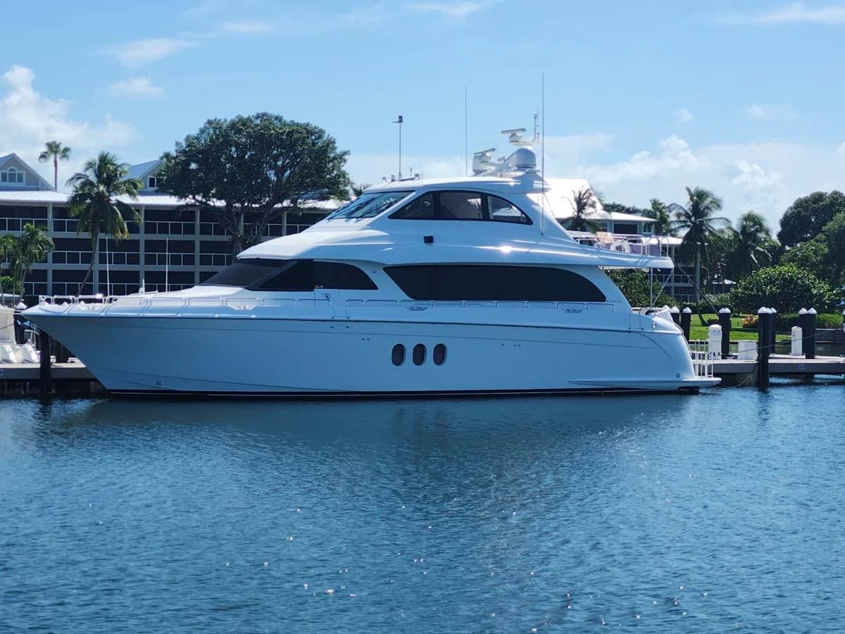 A sleek white yacht is docked in a serene marina under a clear blue sky. aboard SAPPHIRE Yacht for Sale