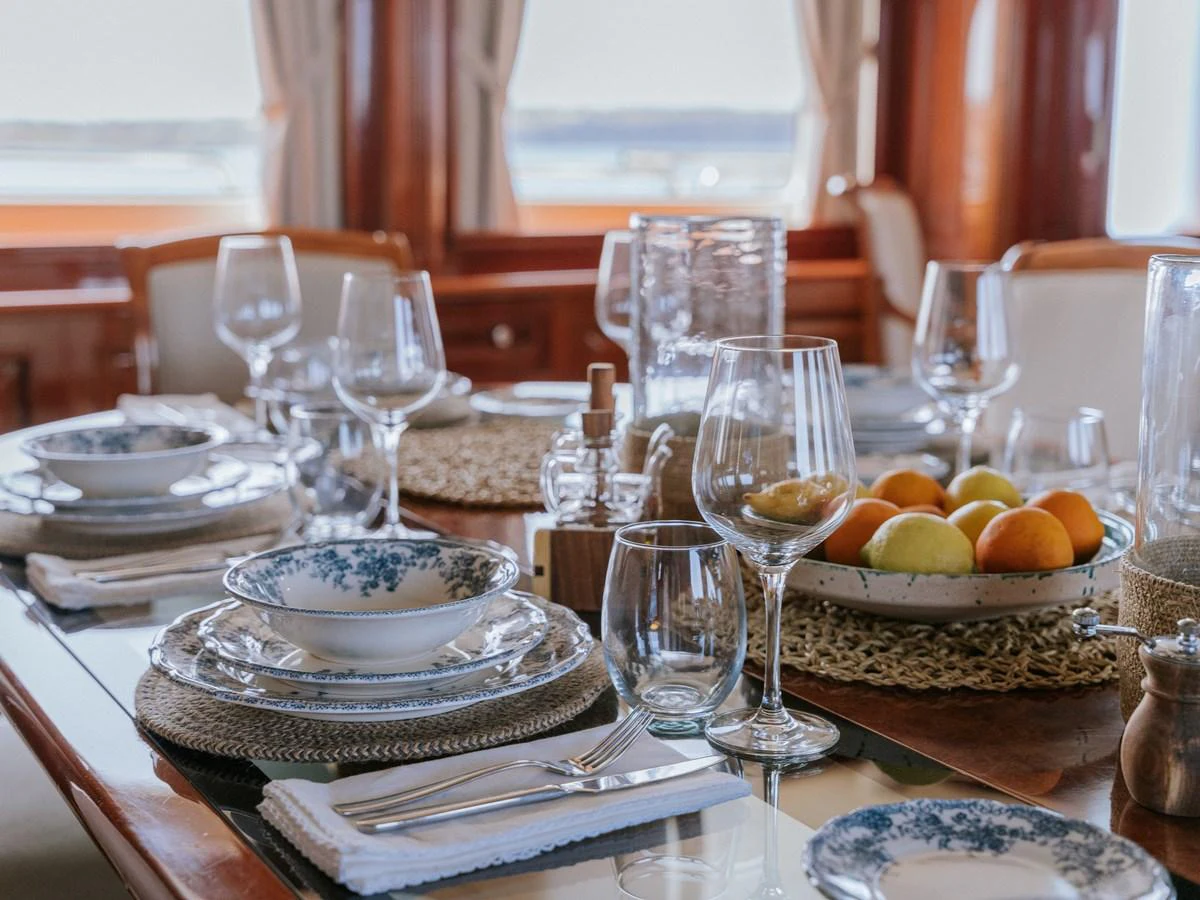 The dining area is elegantly set with fine tableware and a view of the sea through the windows. aboard FRIENDSHIP Yacht for Sale