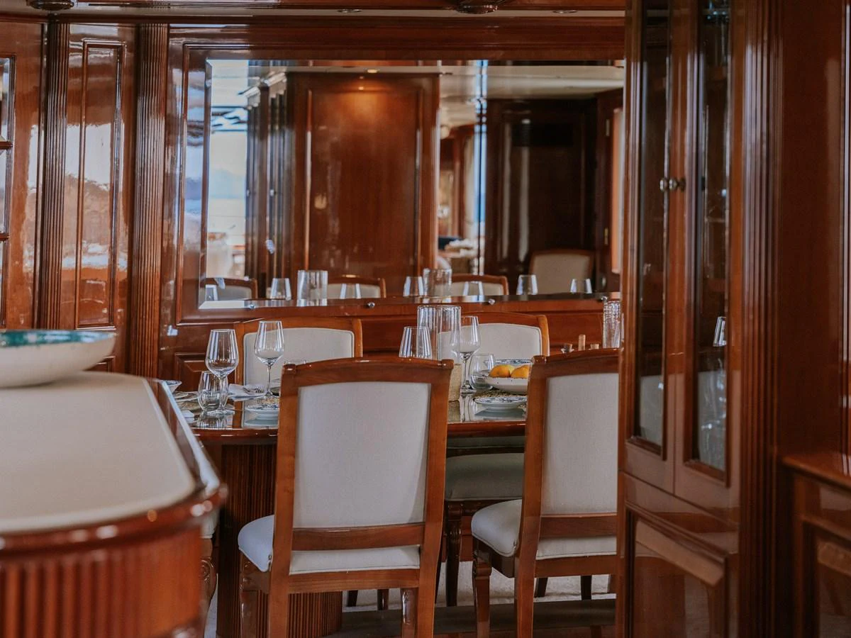 The yacht's dining area features elegant wooden furnishings and a beautifully set table. aboard FRIENDSHIP Yacht for Sale