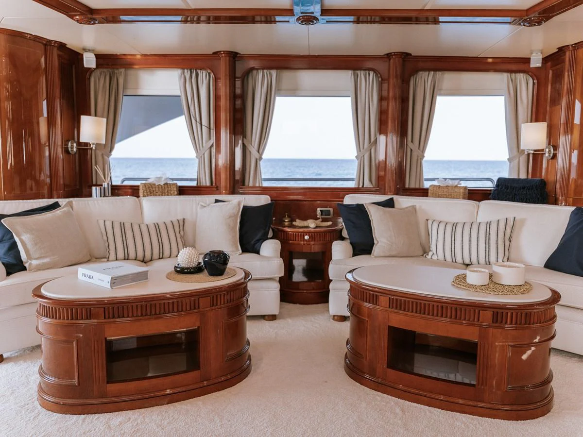 The yacht's interior features a luxurious seating area with elegant wooden furnishings and large windows offering stunning ocean views. aboard FRIENDSHIP Yacht for Sale