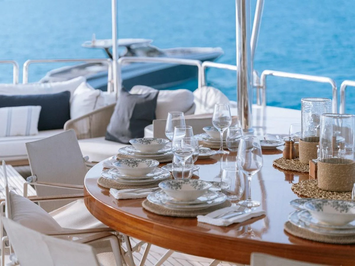 The aft deck features an elegant dining area with a beautifully set table, offering a perfect spot for alfresco meals with a view of the sea. aboard FRIENDSHIP Yacht for Sale