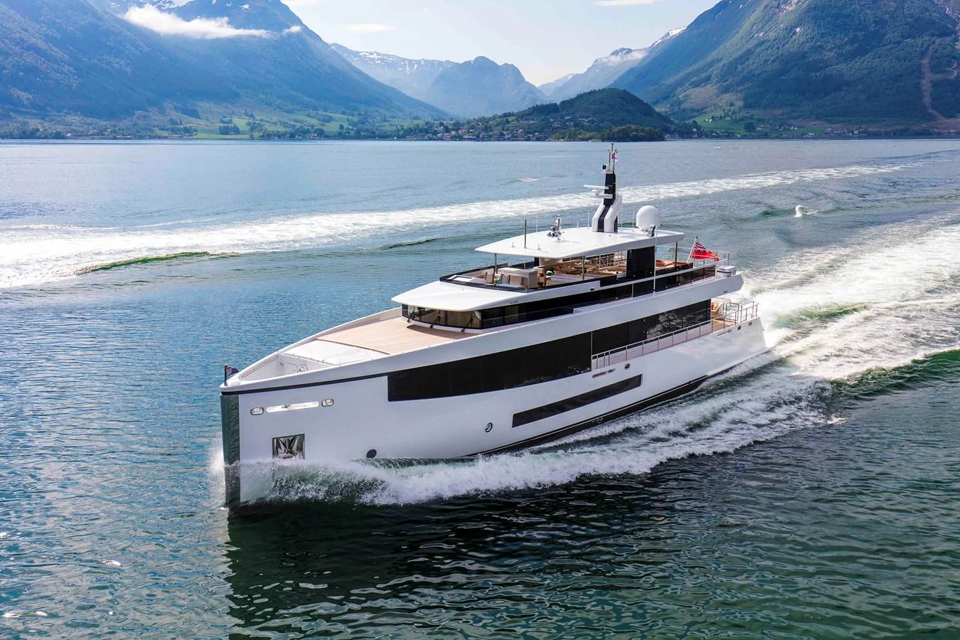 A sleek and modern yacht cruises through scenic waters surrounded by mountains. aboard GRAYCLIFFS Yacht for Sale