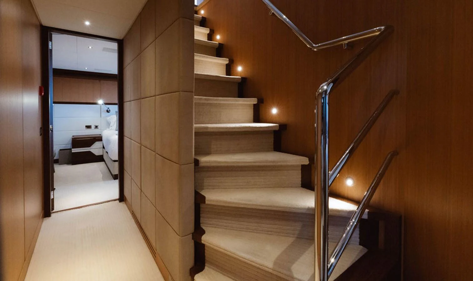 A luxurious staircase with wooden paneling and soft lighting leads to a cozy bedroom. aboard GRAYCLIFFS Yacht for Sale