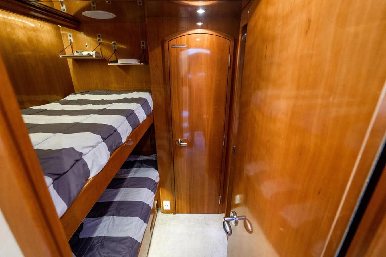 The guest cabin features cozy bunk beds with striped bedding and warm wood paneling. aboard WATER BORN Yacht for Sale