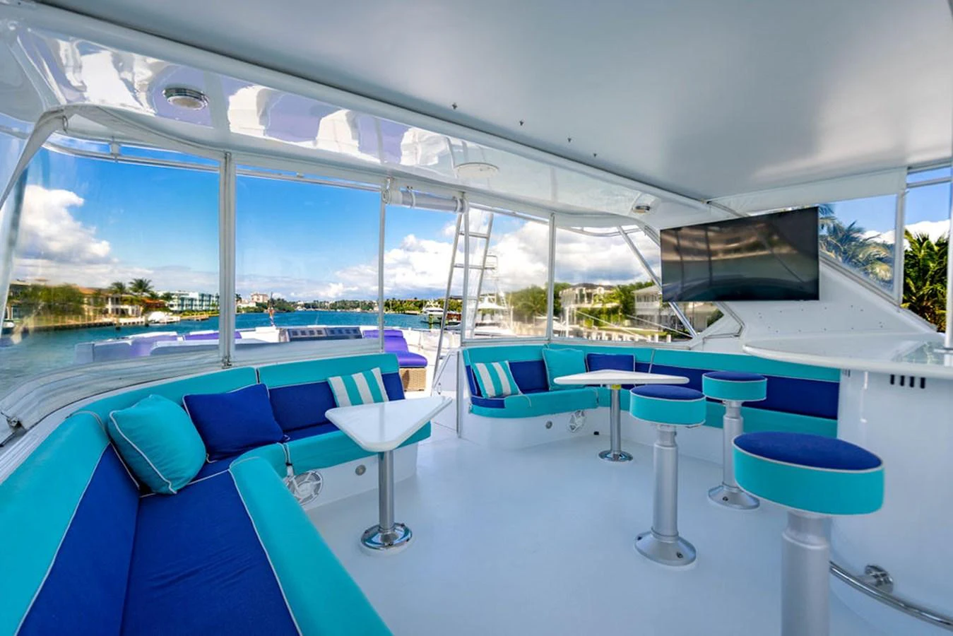 The yacht's salon features vibrant blue and turquoise seating with a panoramic view of the water. aboard WATER BORN Yacht for Sale