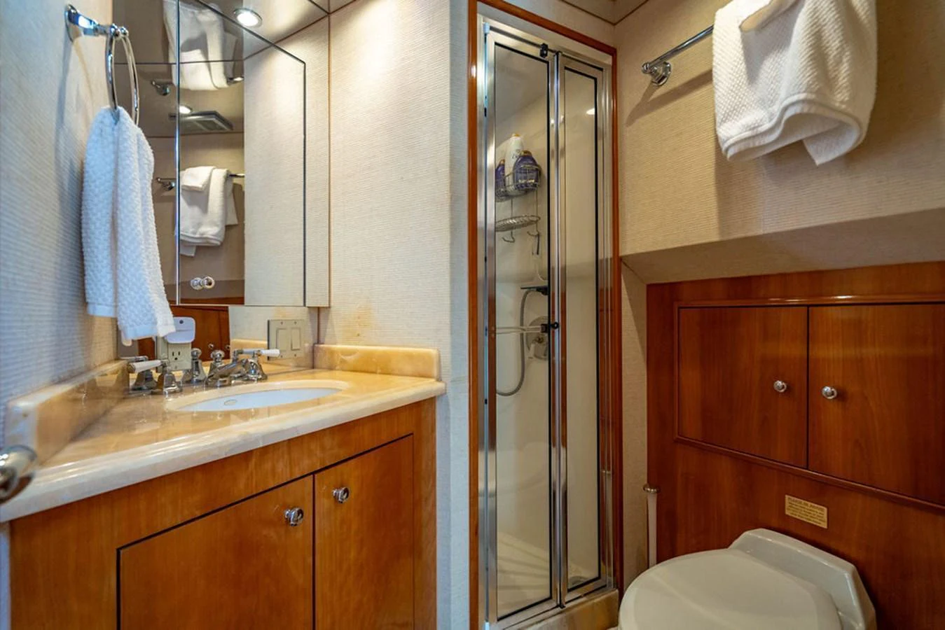 The yacht's bathroom features a sleek design with a glass-enclosed shower and elegant wood cabinetry. aboard WATER BORN Yacht for Sale