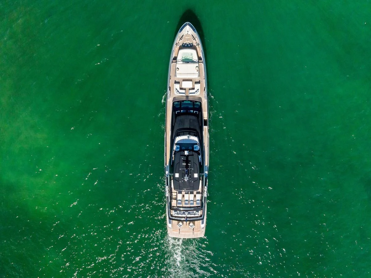 Aerial view of a luxurious yacht cruising through clear green waters. aboard TENACIOUS Yacht for Sale