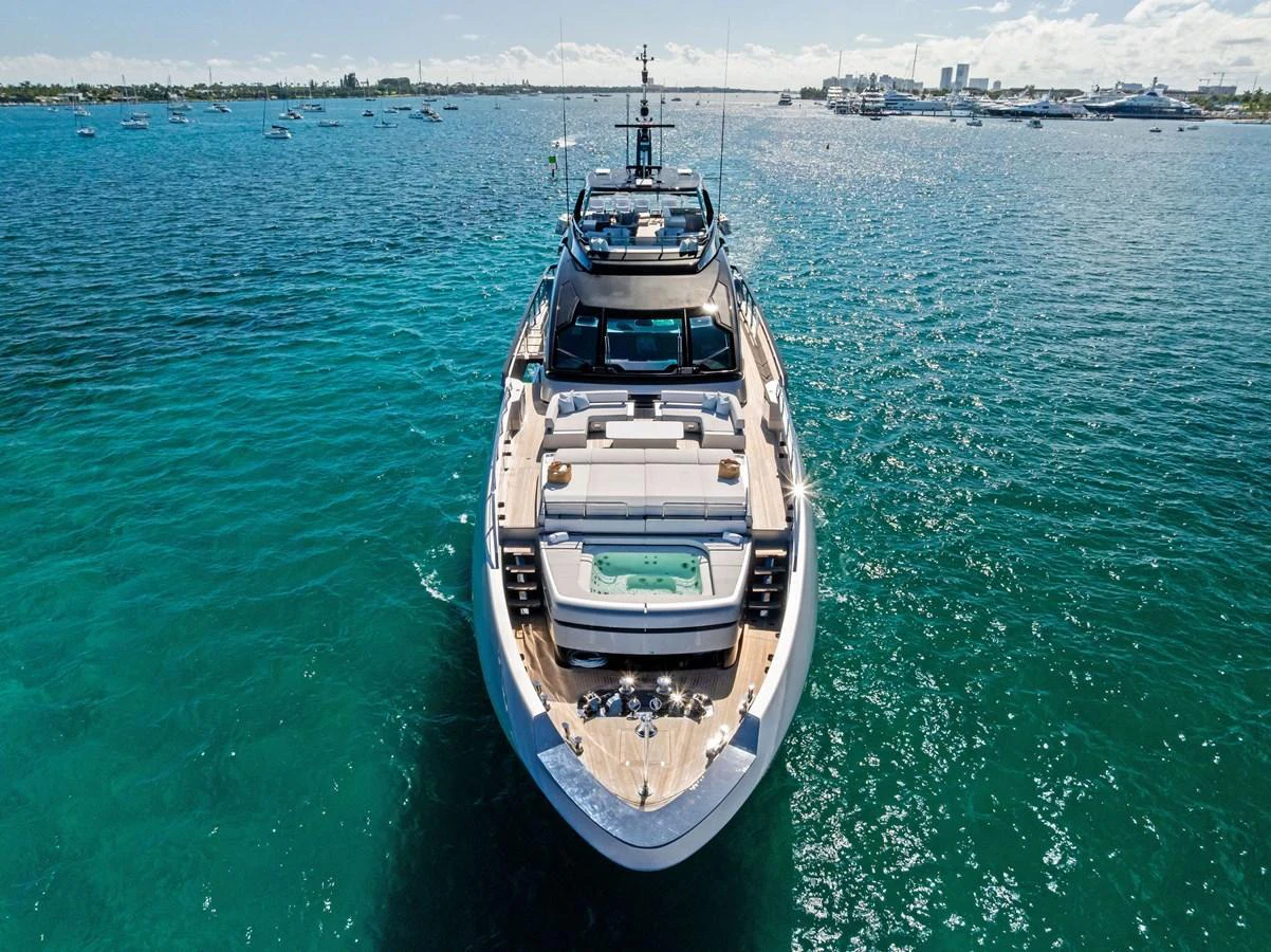 A luxurious yacht is anchored in clear blue waters, showcasing its elegant design and spacious deck areas. aboard TENACIOUS Yacht for Sale