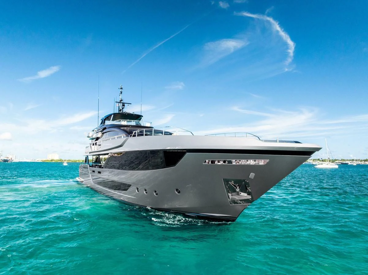 A sleek and modern yacht glides through vibrant turquoise waters under a clear blue sky. aboard TENACIOUS Yacht for Sale