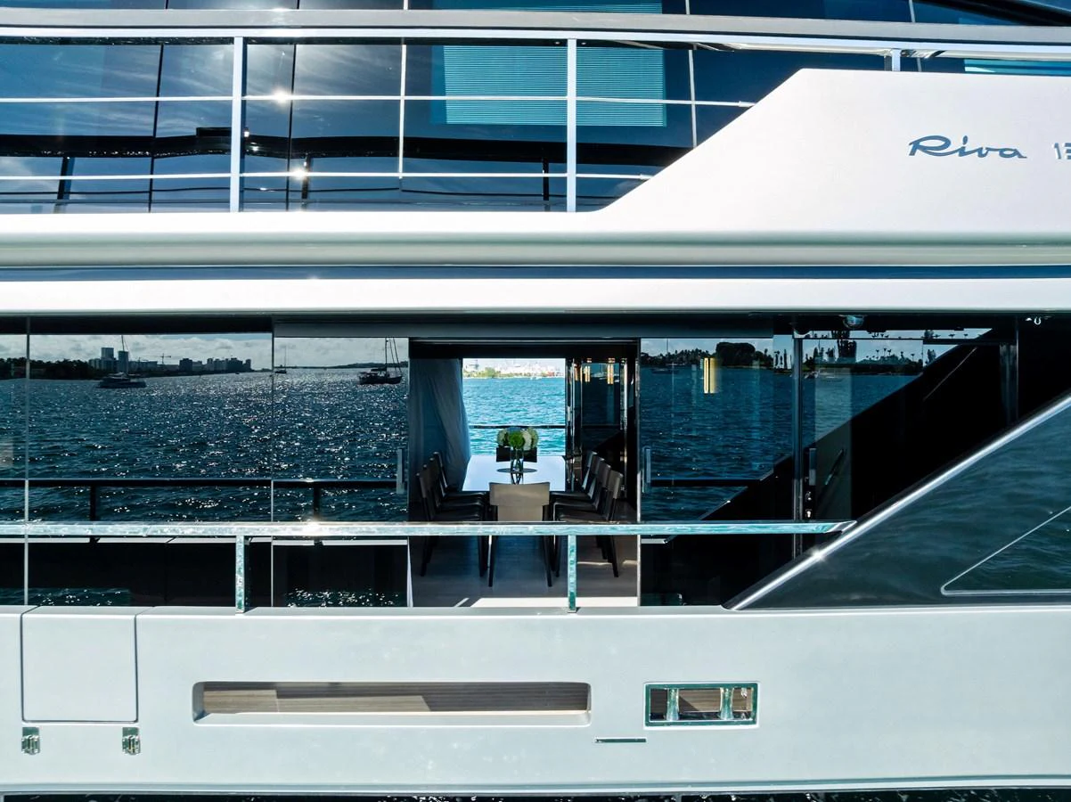 The yacht features sleek, modern lines with expansive windows offering a glimpse of the luxurious interior dining area. aboard TENACIOUS Yacht for Sale