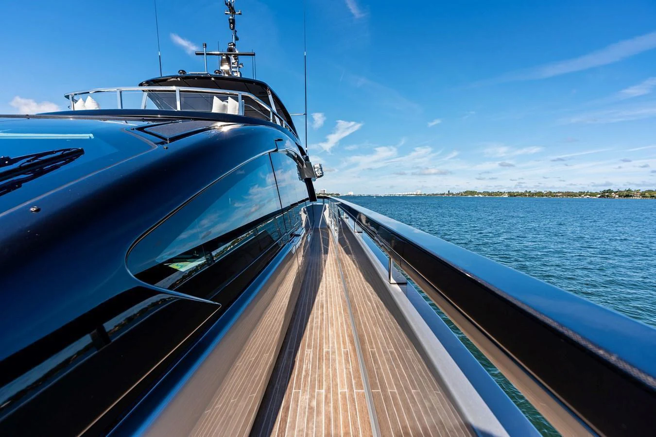 The sleek exterior of the yacht is captured from the side deck, showcasing its modern design and the surrounding serene waters. aboard TENACIOUS Yacht for Sale