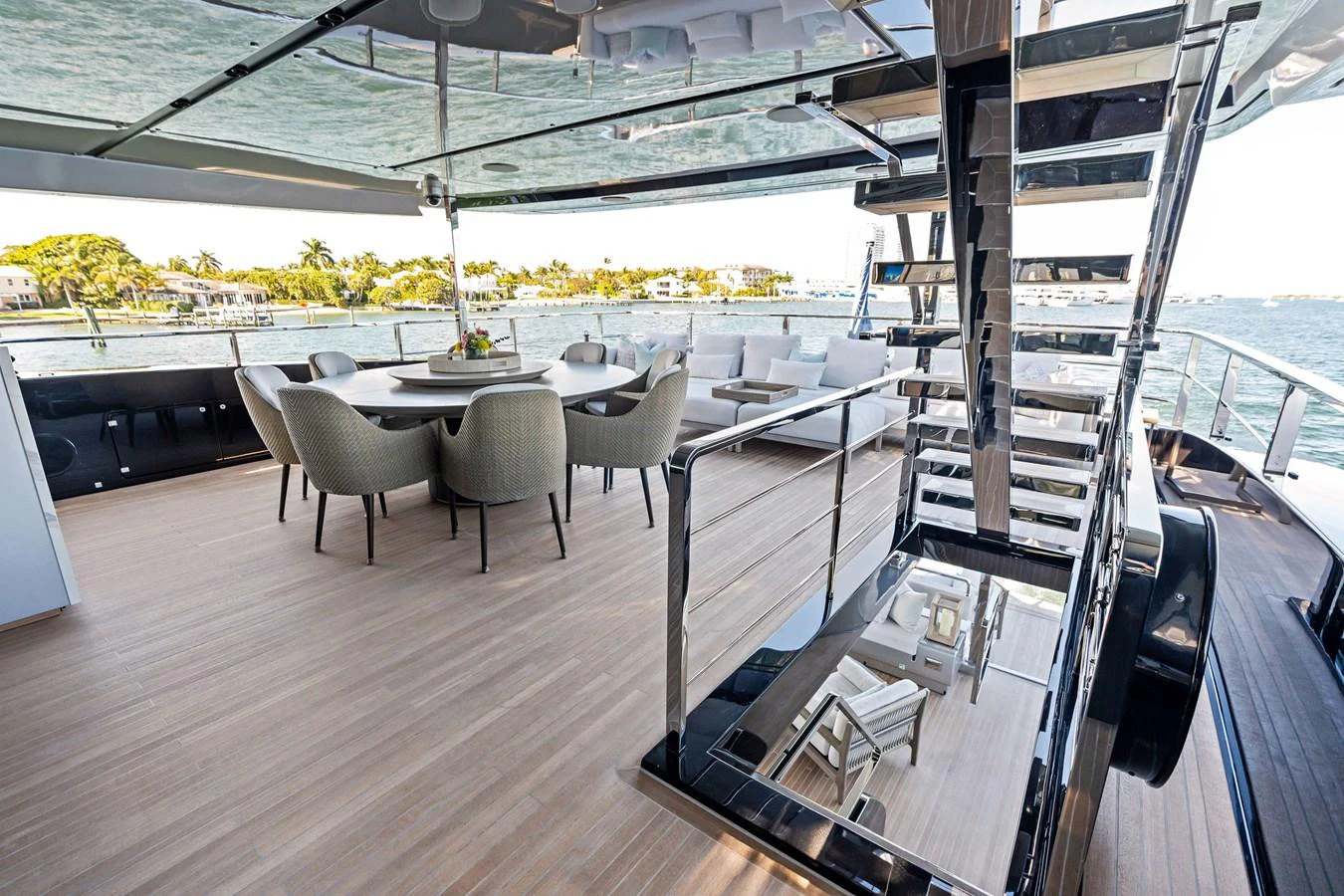 The aft deck features a spacious dining area with elegant seating and a modern staircase leading to the upper deck. aboard TENACIOUS Yacht for Sale