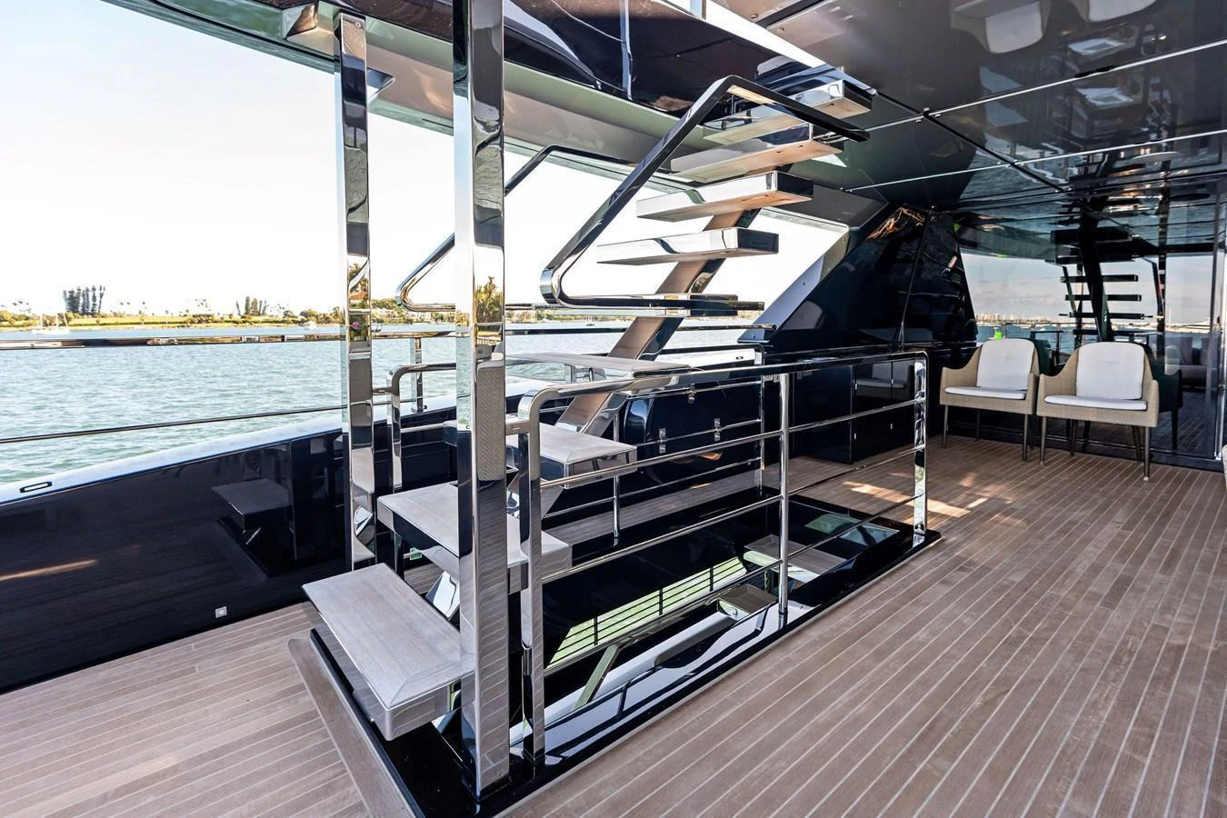 The aft deck features a sleek staircase and comfortable seating with a view of the water. aboard TENACIOUS Yacht for Sale