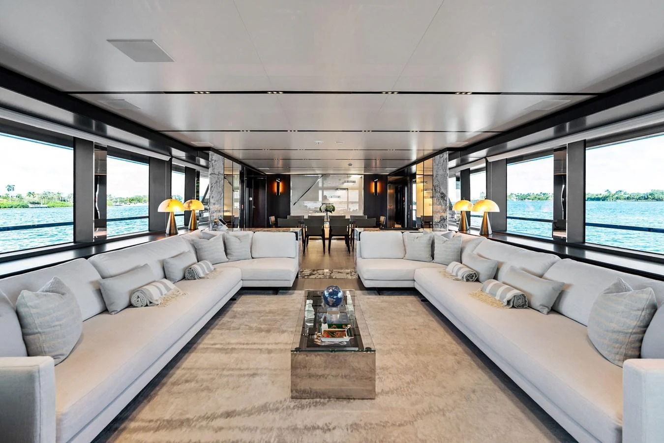 The spacious salon features elegant seating arrangements with panoramic views through large windows. aboard TENACIOUS Yacht for Sale