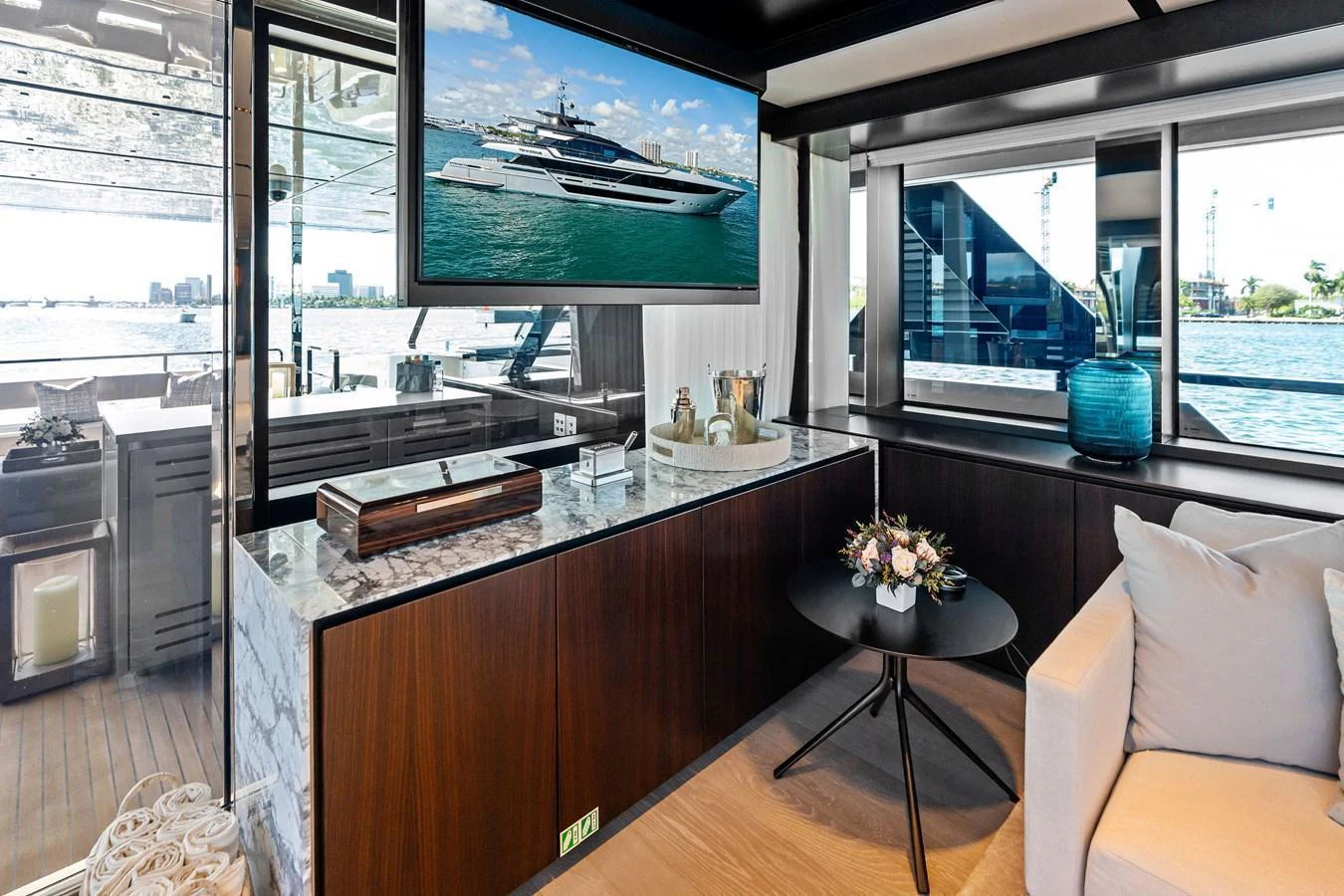 A stylish and modern interior space featuring a comfortable seating area and a large window with a view of the water. aboard TENACIOUS Yacht for Sale