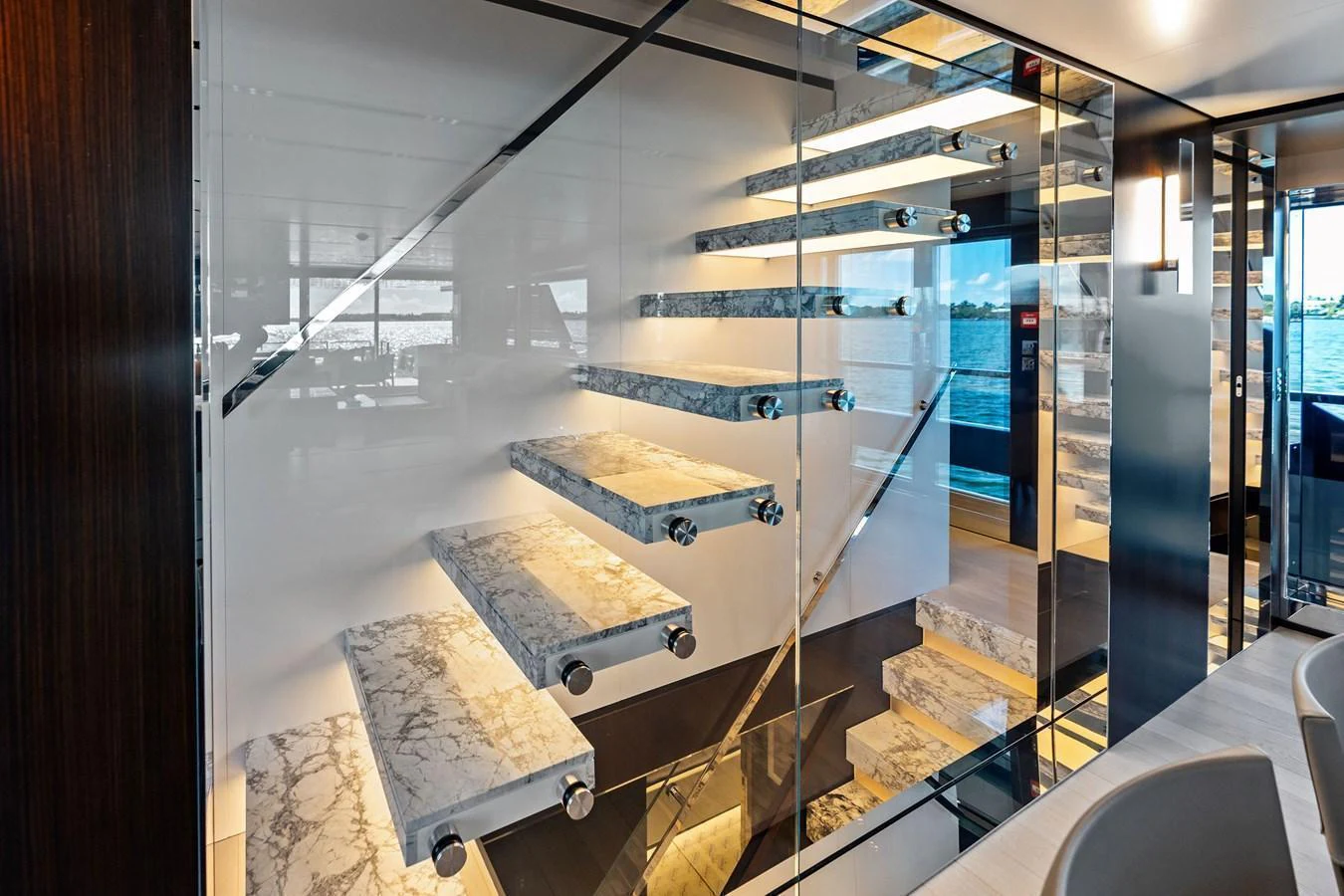A luxurious interior staircase with glass and marble elements, offering a modern and elegant design. aboard TENACIOUS Yacht for Sale