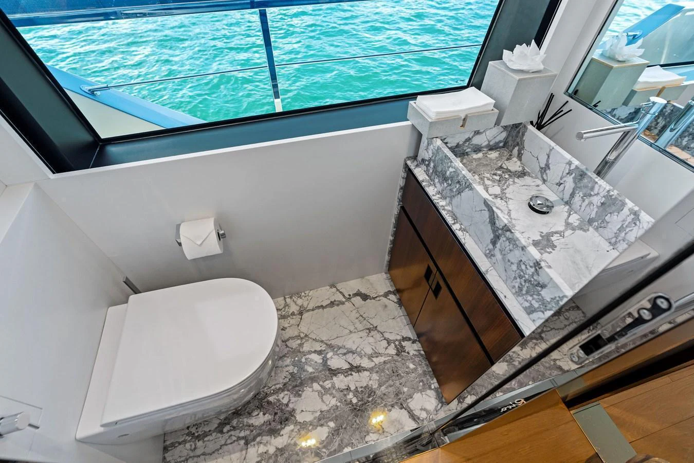 A luxurious yacht bathroom with a marble sink and a large window offering a view of the sea. aboard TENACIOUS Yacht for Sale