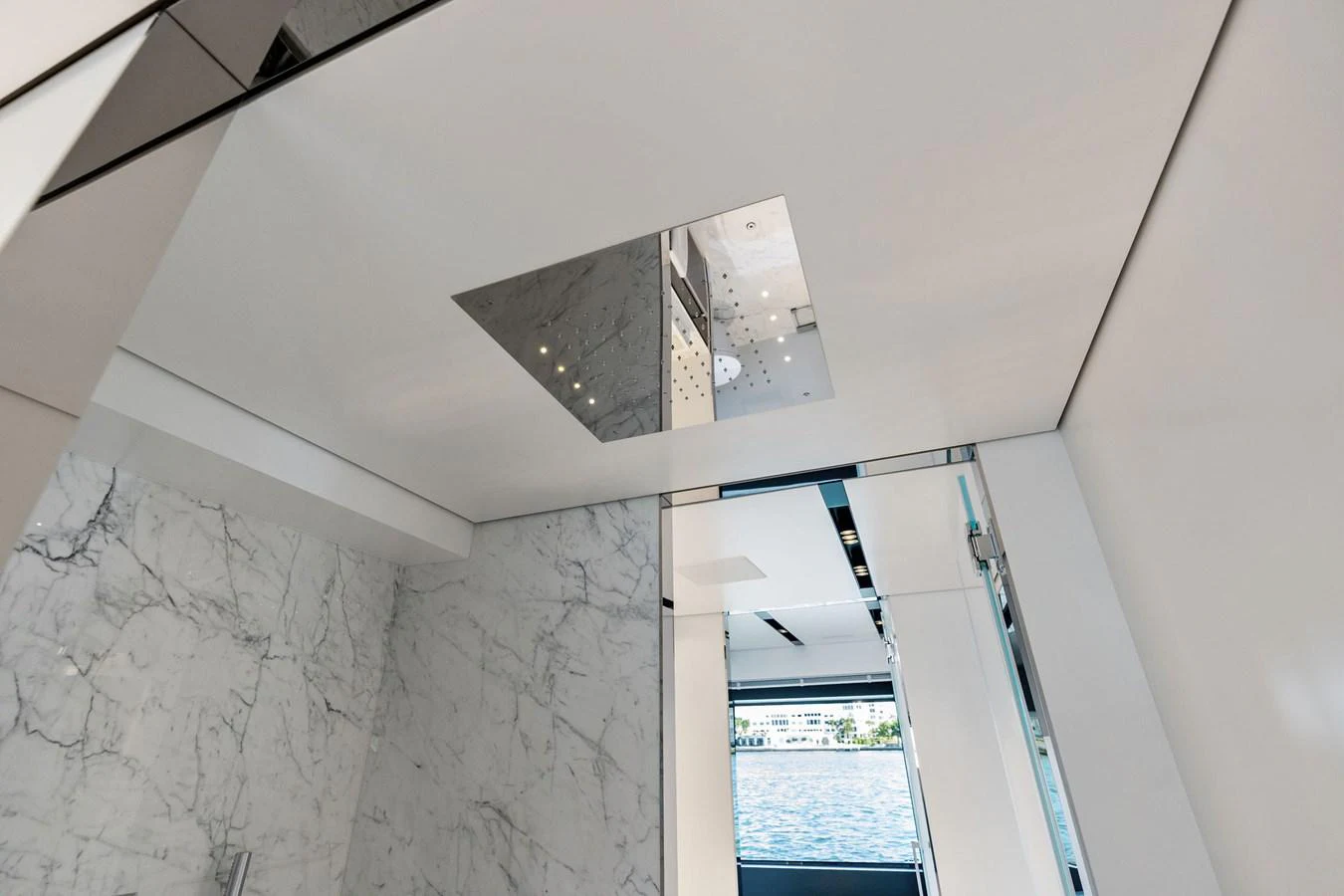 The image showcases a sleek, modern interior with marble accents and a view of the water through a window. aboard TENACIOUS Yacht for Sale