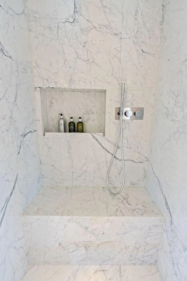 A luxurious marble shower with built-in shelving and modern fixtures. aboard TENACIOUS Yacht for Sale