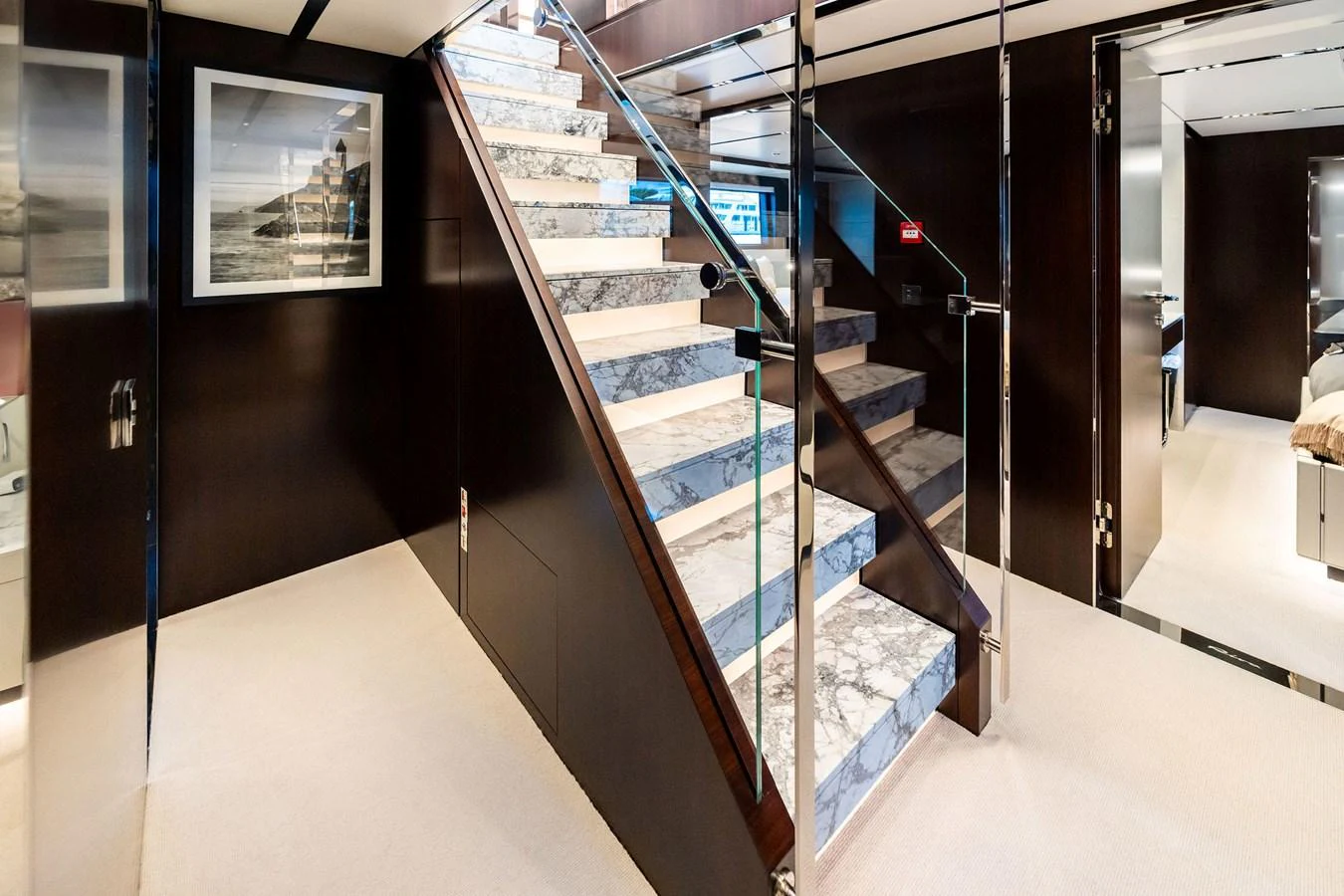 A luxurious interior staircase with marble steps and glass railings. aboard TENACIOUS Yacht for Sale
