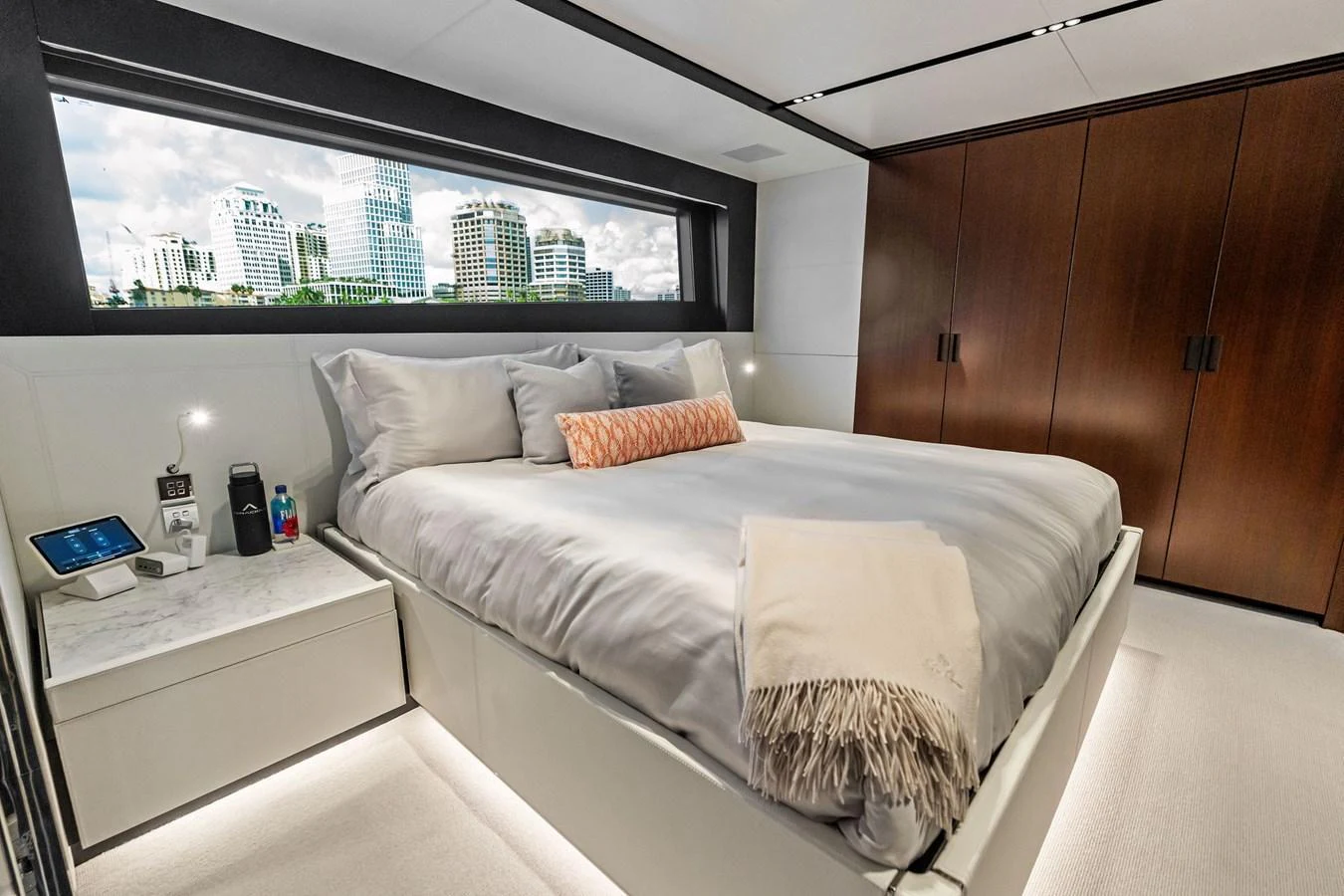 The stateroom features a luxurious bed with a cityscape view through a large window. aboard TENACIOUS Yacht for Sale