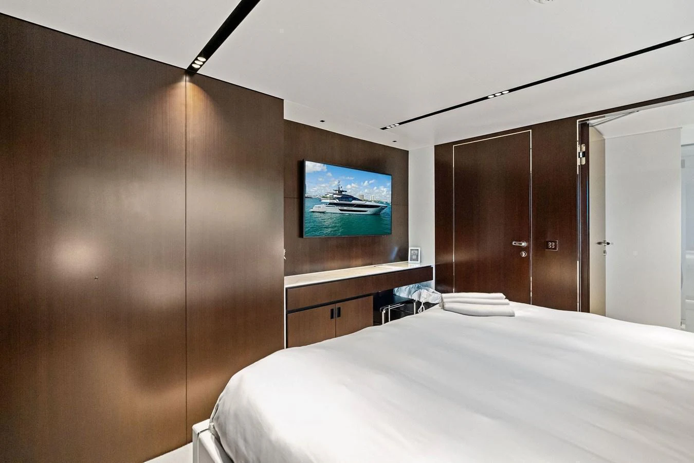 A luxurious stateroom with a large bed, modern decor, and a flat-screen TV displaying a yacht. aboard TENACIOUS Yacht for Sale