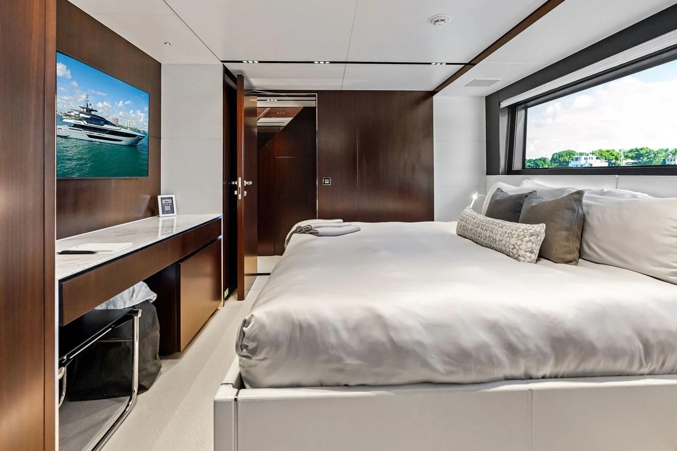 The stateroom features a large bed, a desk area, and a window with a scenic view. aboard TENACIOUS Yacht for Sale