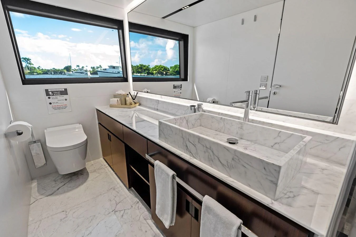 The yacht's bathroom features a sleek, modern design with marble countertops and a large mirror. aboard TENACIOUS Yacht for Sale