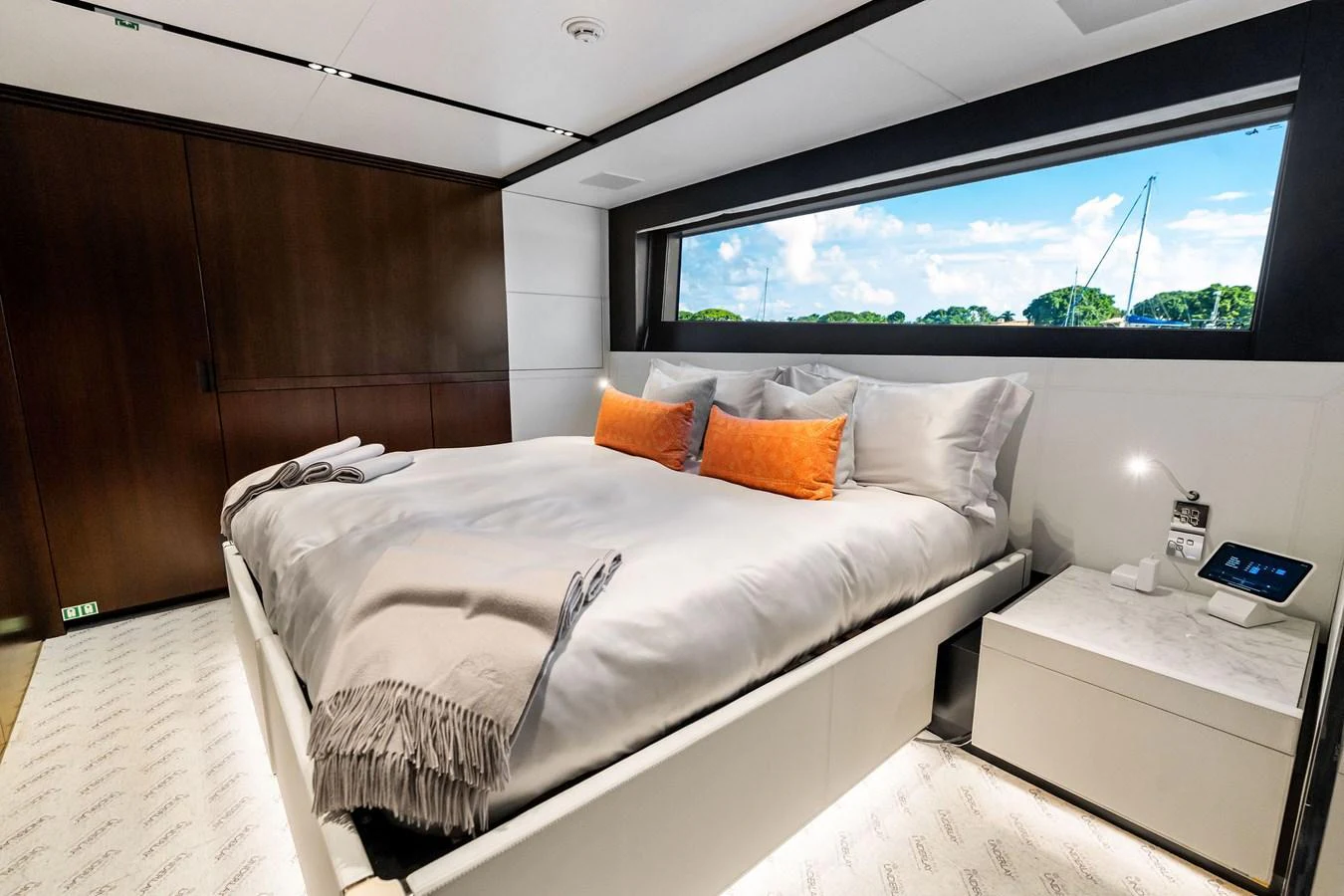 A luxurious stateroom featuring a large bed with plush bedding and a scenic window view. aboard TENACIOUS Yacht for Sale