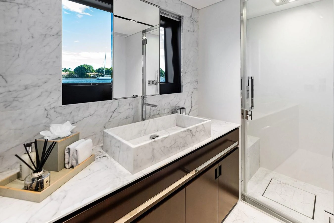 A luxurious yacht bathroom featuring a marble sink and a glass-enclosed shower. aboard TENACIOUS Yacht for Sale