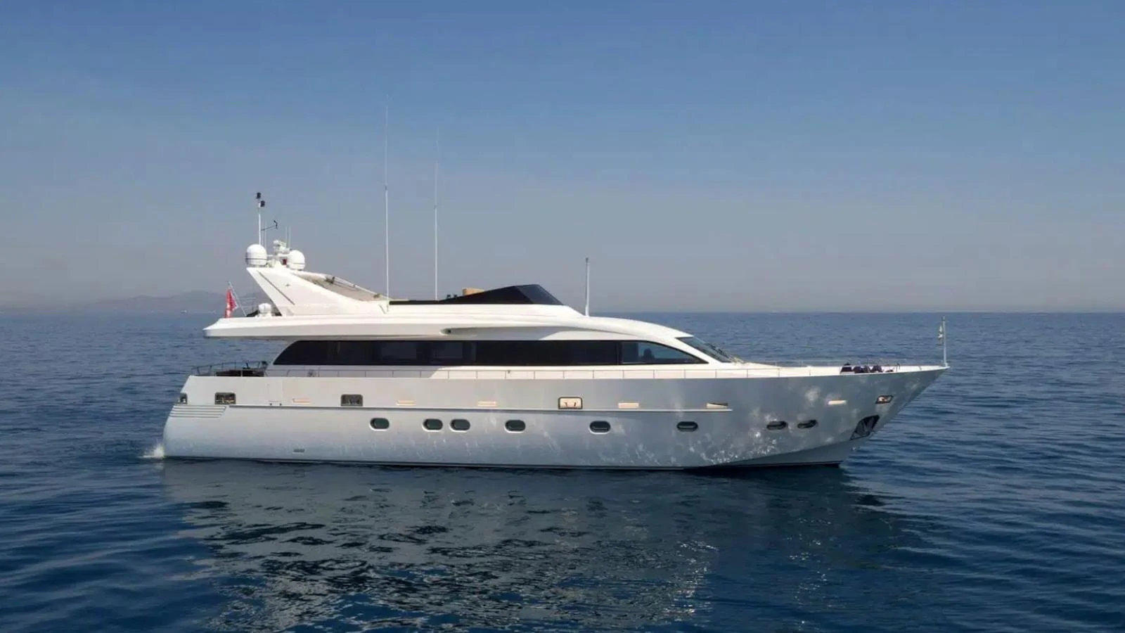 A sleek and elegant yacht cruising on calm waters under a clear sky. aboard MILGAUSS Yacht for Sale
