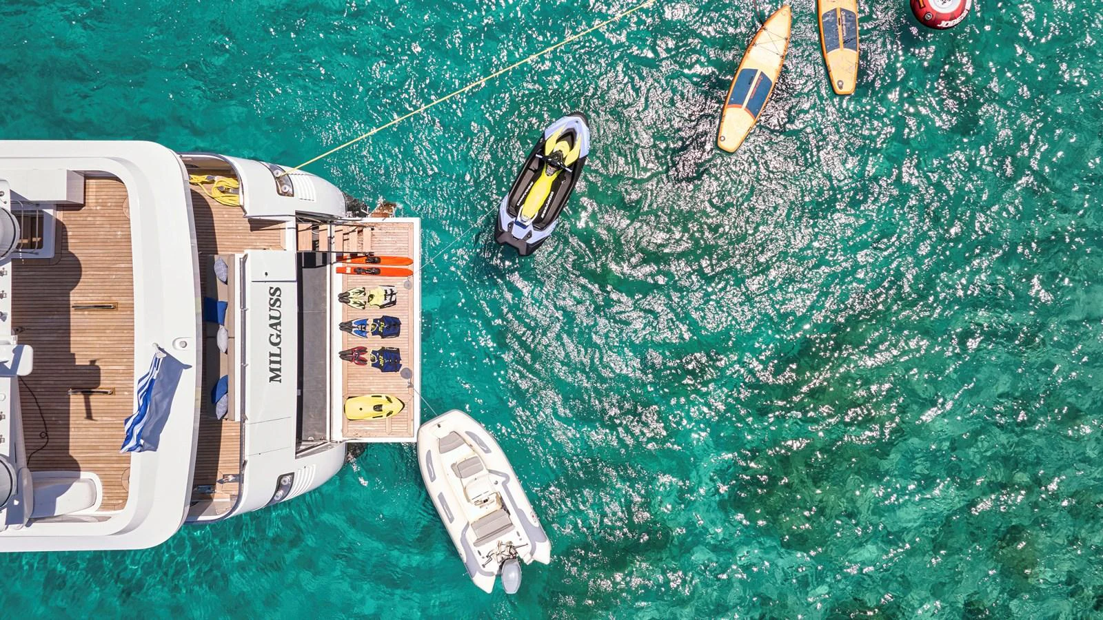 The yacht's swim platform is equipped with various water toys and a tender, perfect for enjoying the clear turquoise waters. aboard MILGAUSS Yacht for Sale